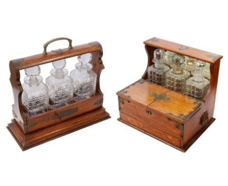 Two Edwardian brass bound oak three bottle tantalus first fitted with square hobnail cut decanters and carrying handle, secon