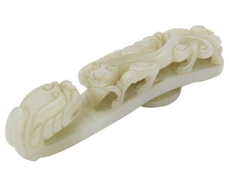 An early 20th century Chinese jade belt hookof typical form, carved to the top in openwork and undercut, at one end with a dr
