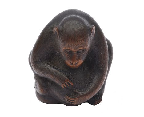 A Japanese Meiji period carved wood netsuke of a monkey naturalistically carved leant forward holding it's young, signed, the