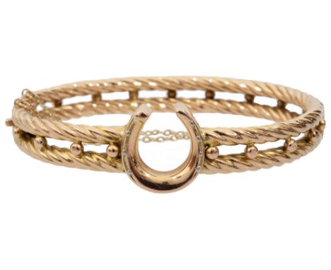 A late 19th century 15ct yellow gold hollow hinged bangle, the central horseshoe held to either side by two rope twist bands 