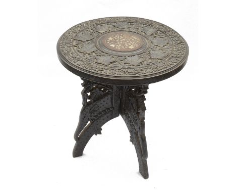 A small 20th century Kashmiri carved hardwood folding side tablethe circular top carved with leaves and flowers, the centre w