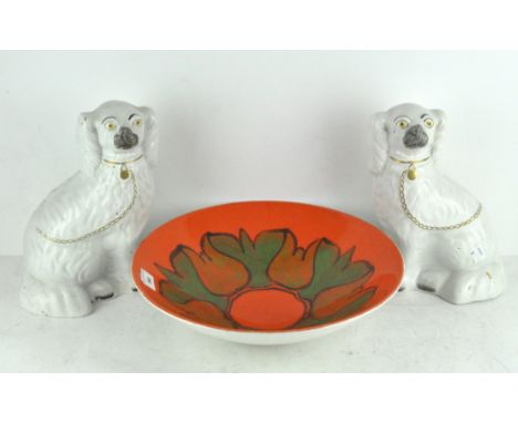 A pair of white glazed Staffordshire dogs together with a Poole pottery bowl with green decorations on an orange glaze