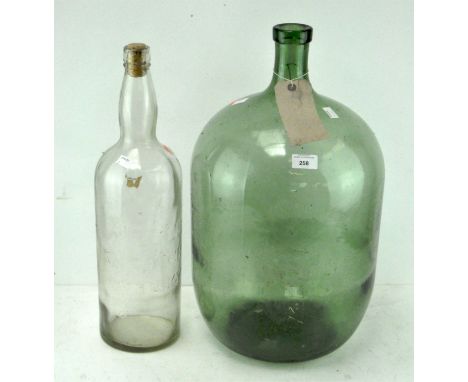 Two large glass bottles, one green, height 54cm, the other clear and stamped 'Bell's Scotch Whisky', height 51cm