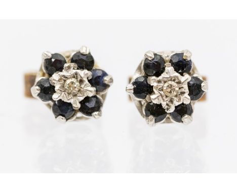 A pair of diamond and sapphire stud earrings, floral clusters set with a small illusion set diamond to the centre within a bo