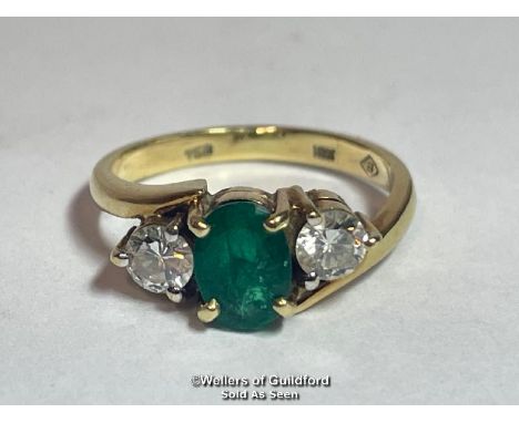 An emerald and diamond three stone ring in crossover style. Emerald measures approx 6.9 x 5.1 x 3.5mm estimated weight 0.73ct