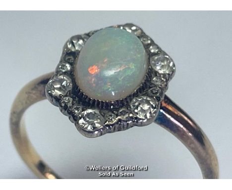 Opal and diamond cluster ring. An oval opal surrounded by a border of old cut diamonds forming a hexagonal cluster. Opal meas