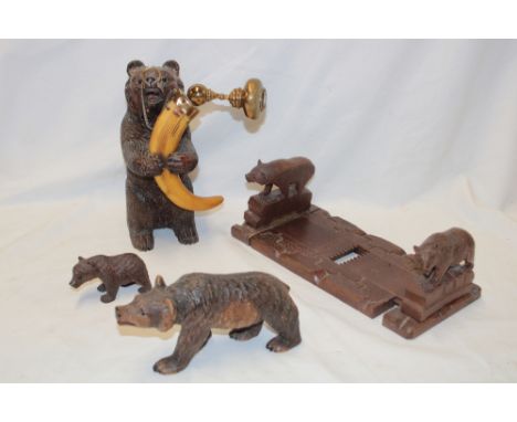 A Black Forest carved wood seated bear figure with glass eyes clutching a boar's tusk with brass mounts, 6" high; two other B