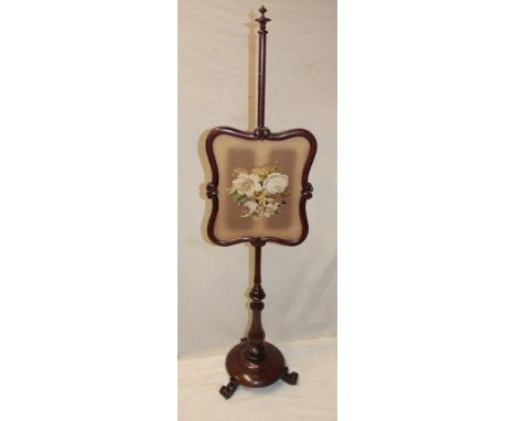 A Victorian rosewood pole screen with a tapestry floral panel on turned column with circular base and scroll feet