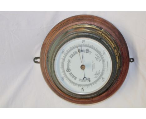 An aneroid barometer by John Barker &amp; Co Kensington with ceramic dial in brass circular case and oak surround