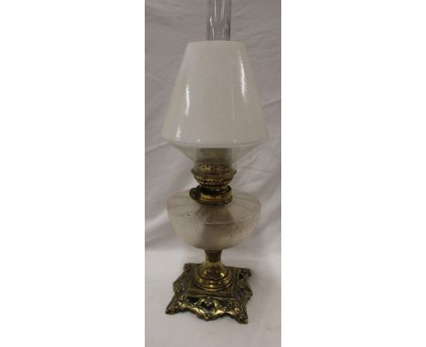 An ornate brass oil lamp with frosted glass circular reservoir and opaque shade, 20" high overall