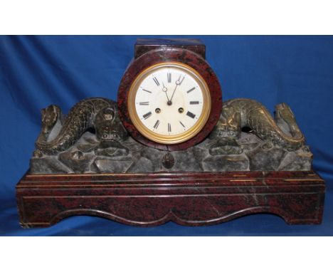 An impressive Cornish serpentine mantel clock with circular enamel dial, carved green serpentine serpent figures within a red