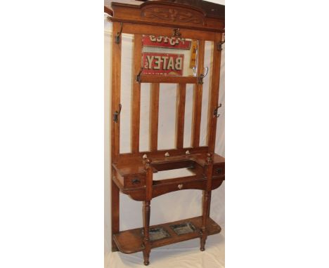 An Art Nouveau carved oak hall stand with central bevelled mirror panel and two small drawers with turned supports