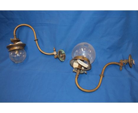 A pair of old brass wall mounted gas light fittings, converted to electric with glass spherical shades