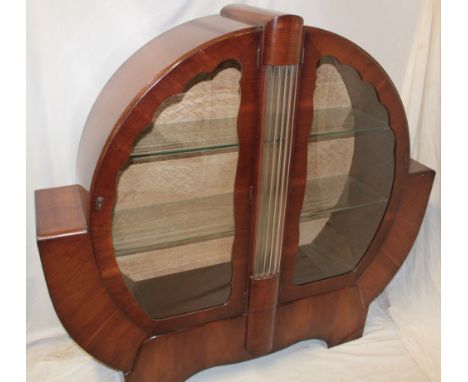 A 1930s Art Deco circular winged display cabinet with glass shelves enclosed by two curved doors and central ribbed glass pan