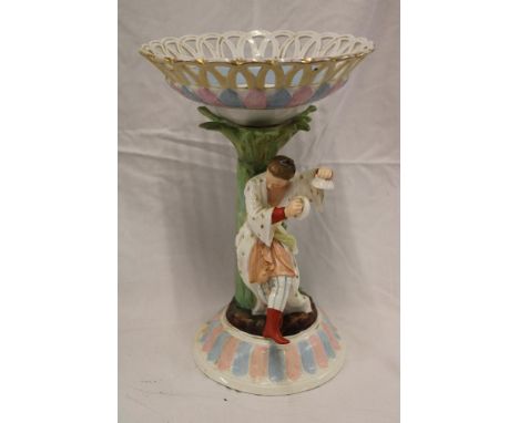 A German porcelain table centre, the stem modelled as a musician by a tree trunk spill supporting an ornamental floral decora