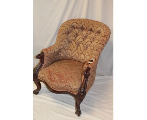 A Victorian carved mahogany easy chair upholstered in button fabric on scroll-shaped legs
