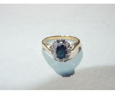 An 18ct gold lady's cluster ring with a central oval sapphire surrounded by 8 illusion diamonds (one missing), size L