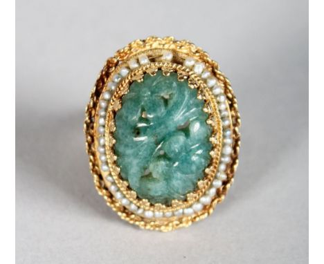 A GOLD AND JADE RING, the oval jade stone with carved decoration, surrounded by seed pearls.