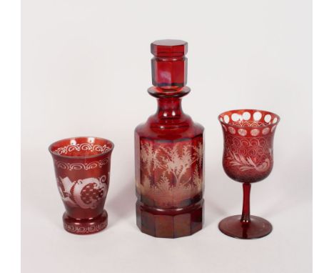 A BOHEMIAN RUBY DECANTER AND STOPPER engraved with deer in a landscape, 10ins high, a beaker and a goblet.