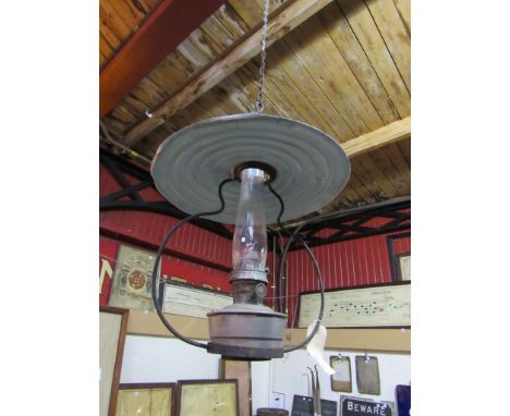 A railway signal box ceiling hanging oil lamp with reservoir, glass chimney and overhanging metal deflector 