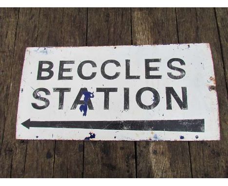 An enamel "BECCLES STATION" sign with arrow pointing to the left, black lettering on white background, previously a "NO PARKI