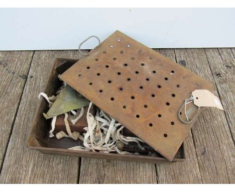 A tin box containing various oil lamp accessories including wicks, burners 
