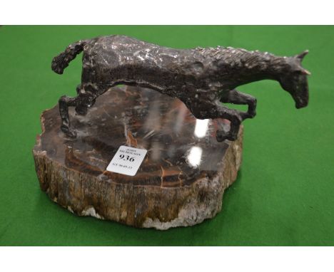 A white metal model of a rearing horse on hard stone base.