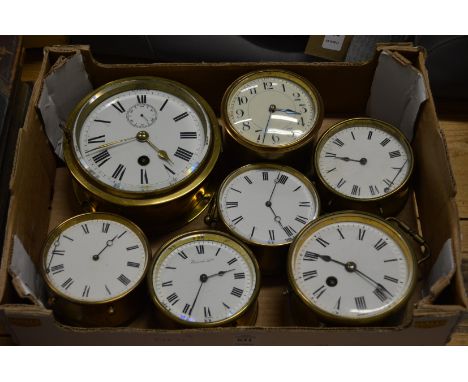 A brass ships clock and six similar brass circular bedside/mantle clocks.