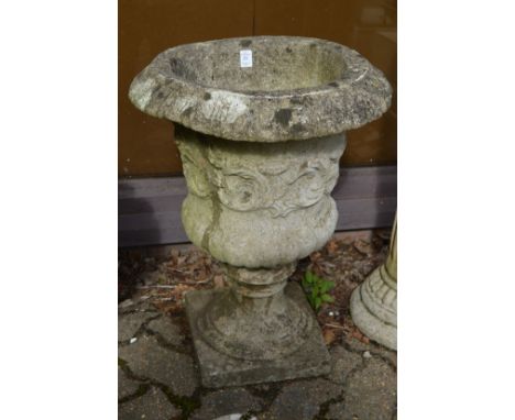 A pair of reconstituted stone pedestal urn shaped planters.