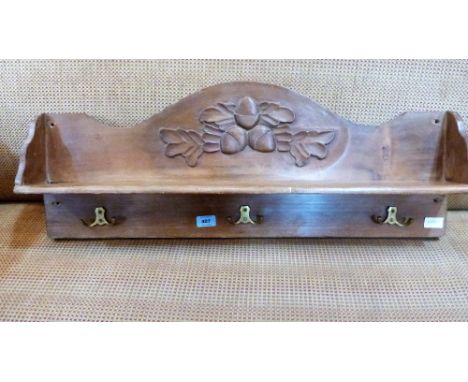 A pine wall shelf carved with acorns and fitted with three double coat hooks. 32'' wide