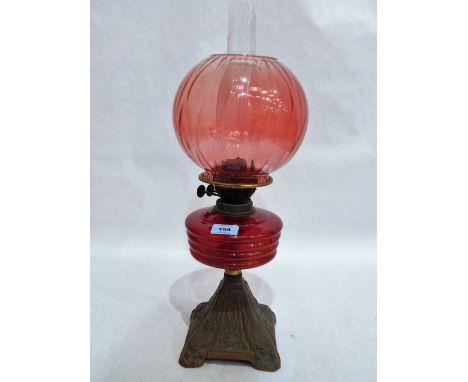 A Victorian oil lamp with ruby glass shade and fount on cast iron base. 19'' high