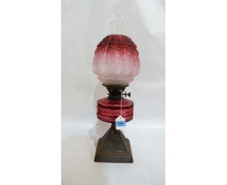 A Victorian oil lamp, Hinks No.2 duplex burner, with ruby flashed acid etched shade, cranberry fount and iron pyramid base. 2