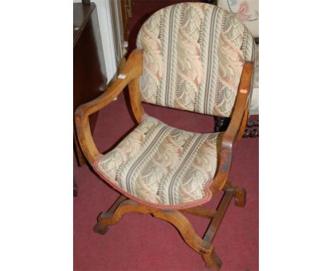 An early 20th century Spanish style walnut and floral tapestry upholstered X-framed elbow chair 