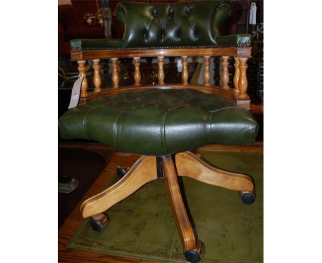 A reproduction green leather button back revolving tub desk chair