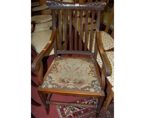 An early 20th century floral carved oak slatback elbow chair, having tapestry upholstered fixed pad seat