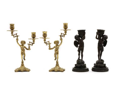 A pair of brass figural candlesticks modelled as putti holding two branches with sconces, 29cm hightogether with two further 