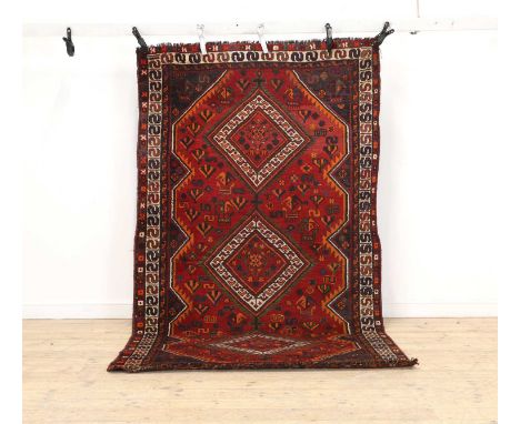 A tribal wool rug 20th century, woven with three diamond medallions to a red ground,284 x 155cmCondition ReportSome light fad