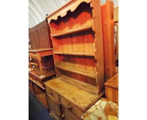 A vintage pine dresser having three shelf plate rack, the base having two drawers over opening cupboard space