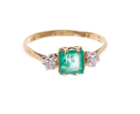 Emerald and diamond three stone ring with a square step cut emerald measuring approximately 5.9mm x 5.9mm x 2.9mm, flanked by