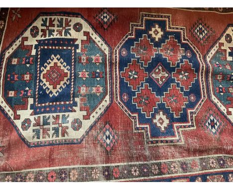 Tribal rug with three geometric medallions on brick red ground, 210 x 140cm
