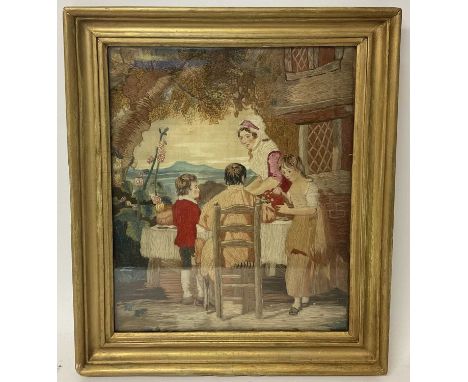 Georgian woolwork picture after George Morland, depicting a family sitting at a table outside a cottage, in glazed gilt frame