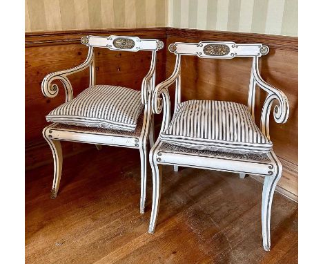 Pair of Regency-style white painted and parcel gilt open elbow chairs with cane seats on sabre legs, with striped fabric cush