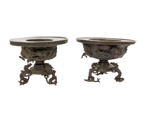 Matched pair of Chinese bronze censers on dragon feet, each with broad dished circular top moulded with dragons, raised on sp