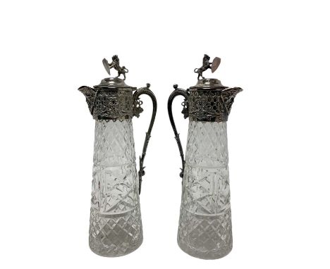 Pair of post war moulded glass claret jugs, with ornate silver plated mounts and hinged covers, with lion and shield finials.