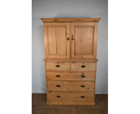 Victorian pine livery cupboard, enclosed by twin doors above on base with two short over three long graduated drawers on plin