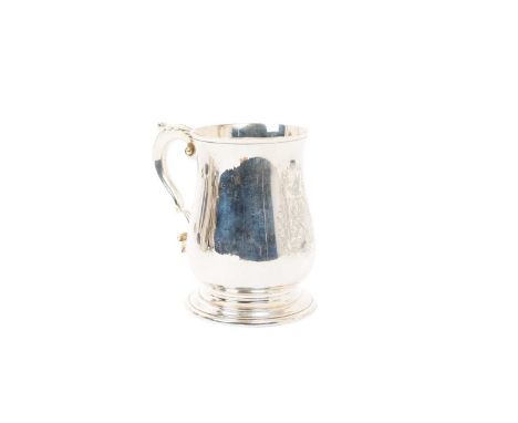 Contemporary silver mug of baluster form, with engraved armorial and leaf mounted scroll handle, on a circular base (London 1