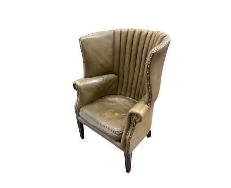 George III style leather upholstered barrel back armchair, raised on reeded tapered legsLeather has wear abd fading to extrem