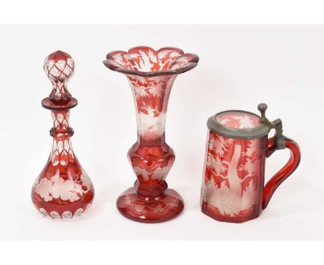 Three pieces of Bohemian flash cut ruby glassware, including a tankard and vase cut and engraved with stags, and a bottle and