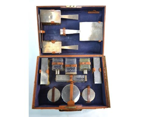 A leather toilet case, fitted with an engine-turned silver gilt dressing set, with floral-cut and fluted glass bottles and ja