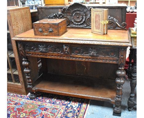 A Gothic revival carved oak console table with raised back over two frieze drawers and turned supports with open under-tier, 